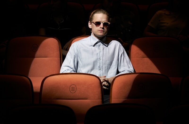 man in blue dress shirt wearing sunglasses sitting on brown chair